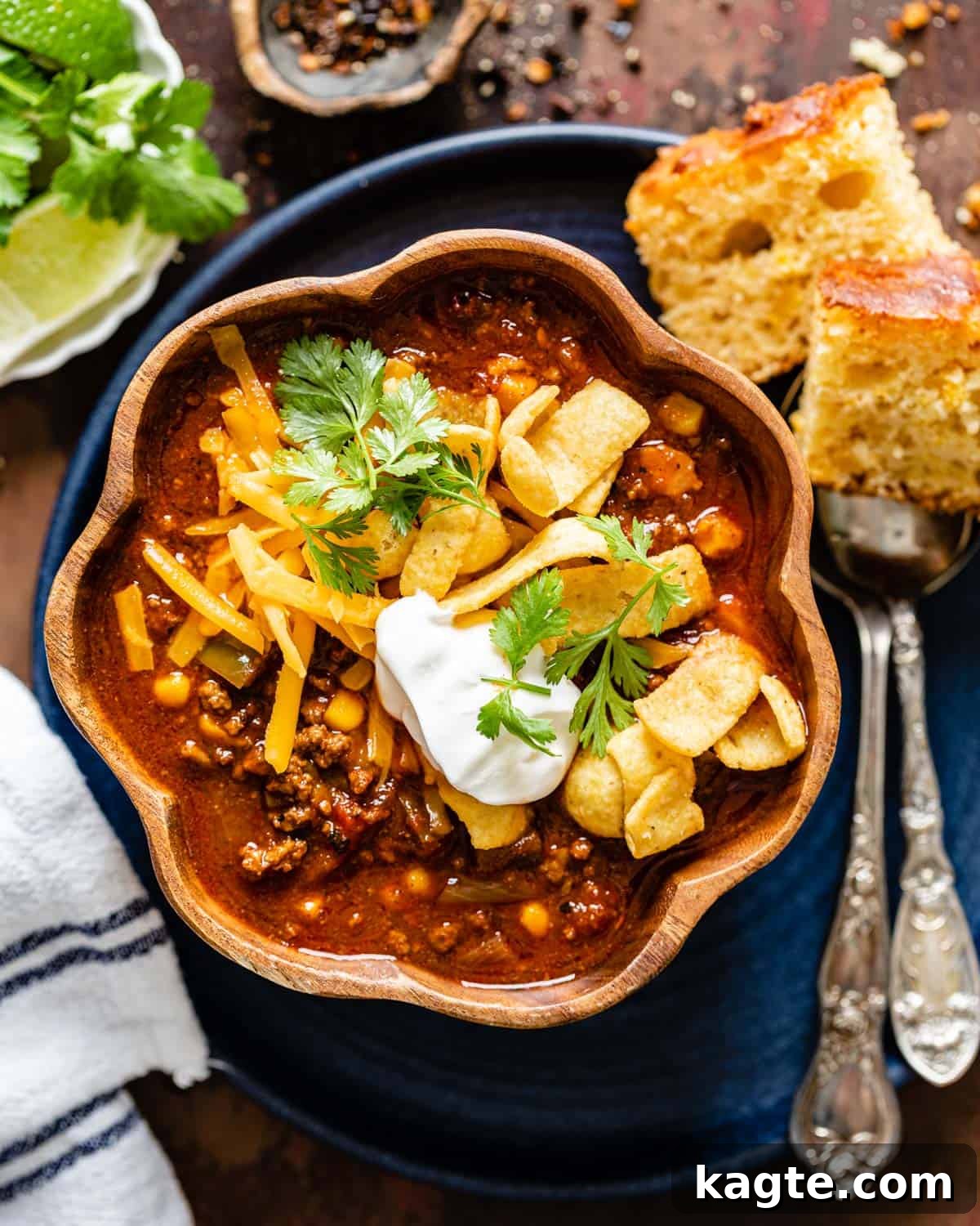 overhead of chili in a wood bowl, garnished with fresh herbs and a dollop of sour cream