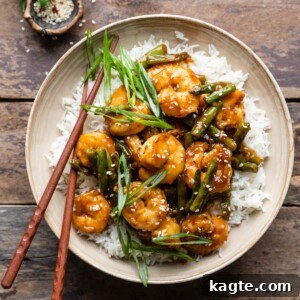 Hunan Shrimp served in a cream-colored bowl with white rice and green onions.