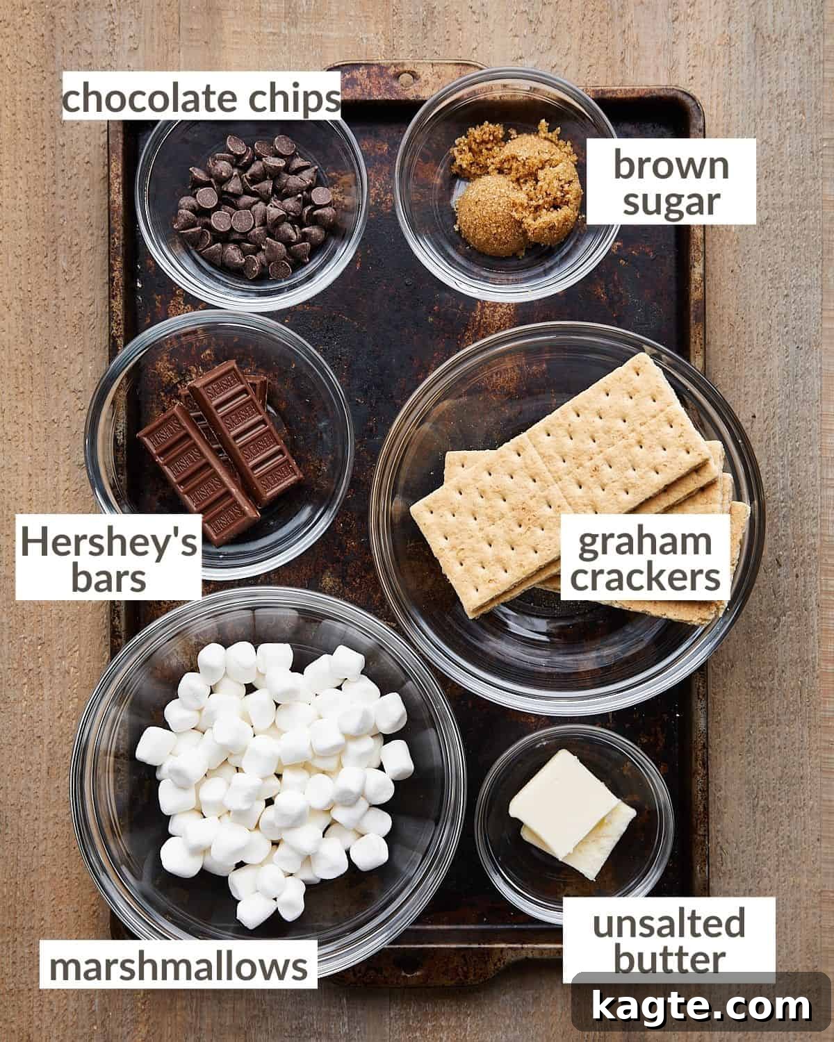 Individual Graham Cracker S'mores Tartlets 3 Overhead image of ingredients needed to make mini s'mores pies, including graham crackers, chocolate bars, marshmallows, butter, and brown sugar.