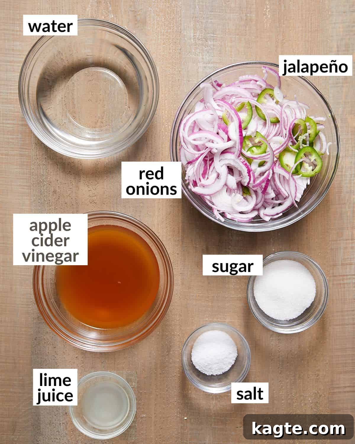 Zesty Mexican Pickled Onions 3 A flat lay photograph showcasing the simple ingredients needed to make Mexican pickled onions: sliced red onions, jalapeños, lime, sugar, salt, water, and apple cider vinegar, all arranged in glass bowls.