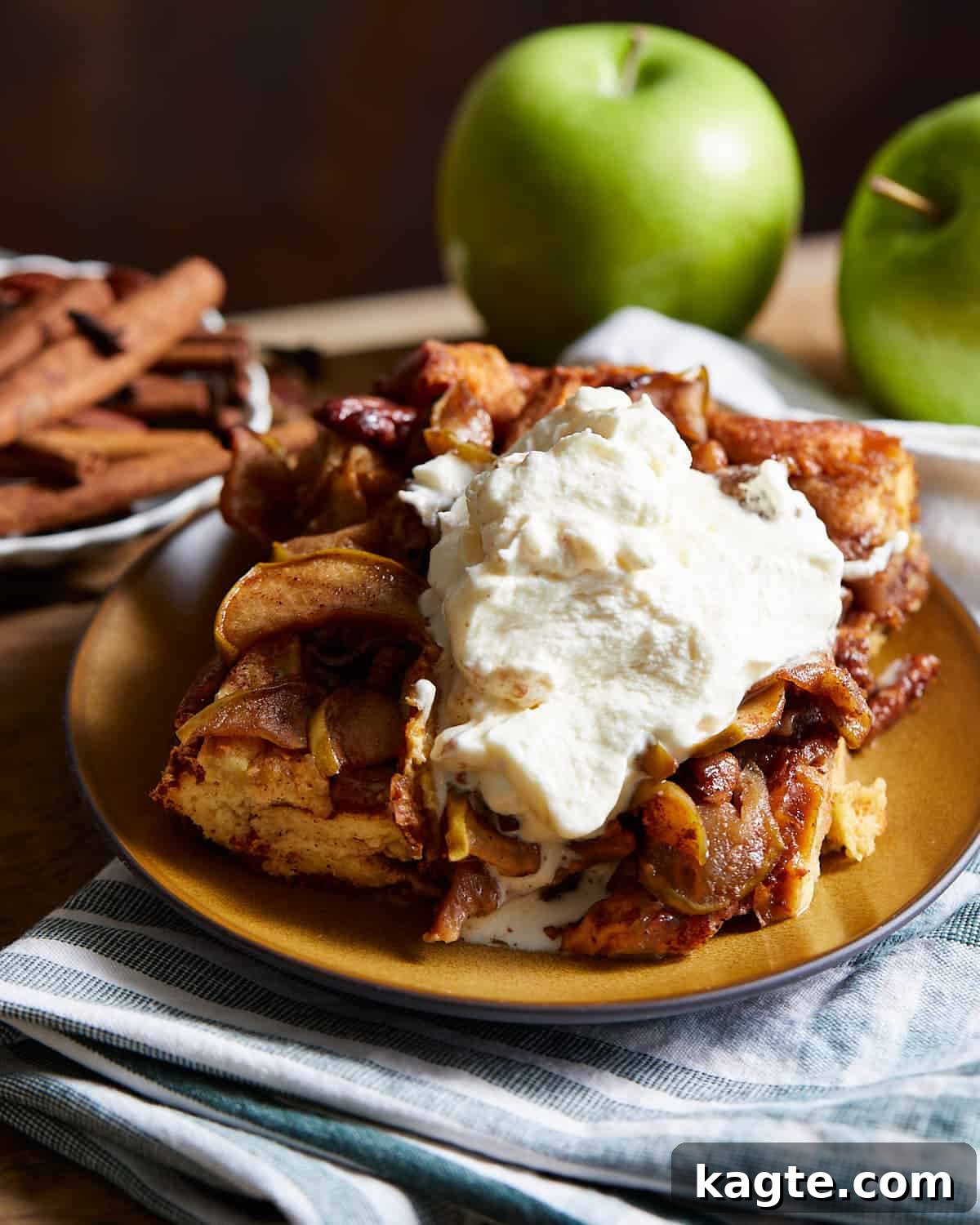 A delectable slice of apple bread pudding garnished with homemade whipped cream and a sprinkle of cinnamon.