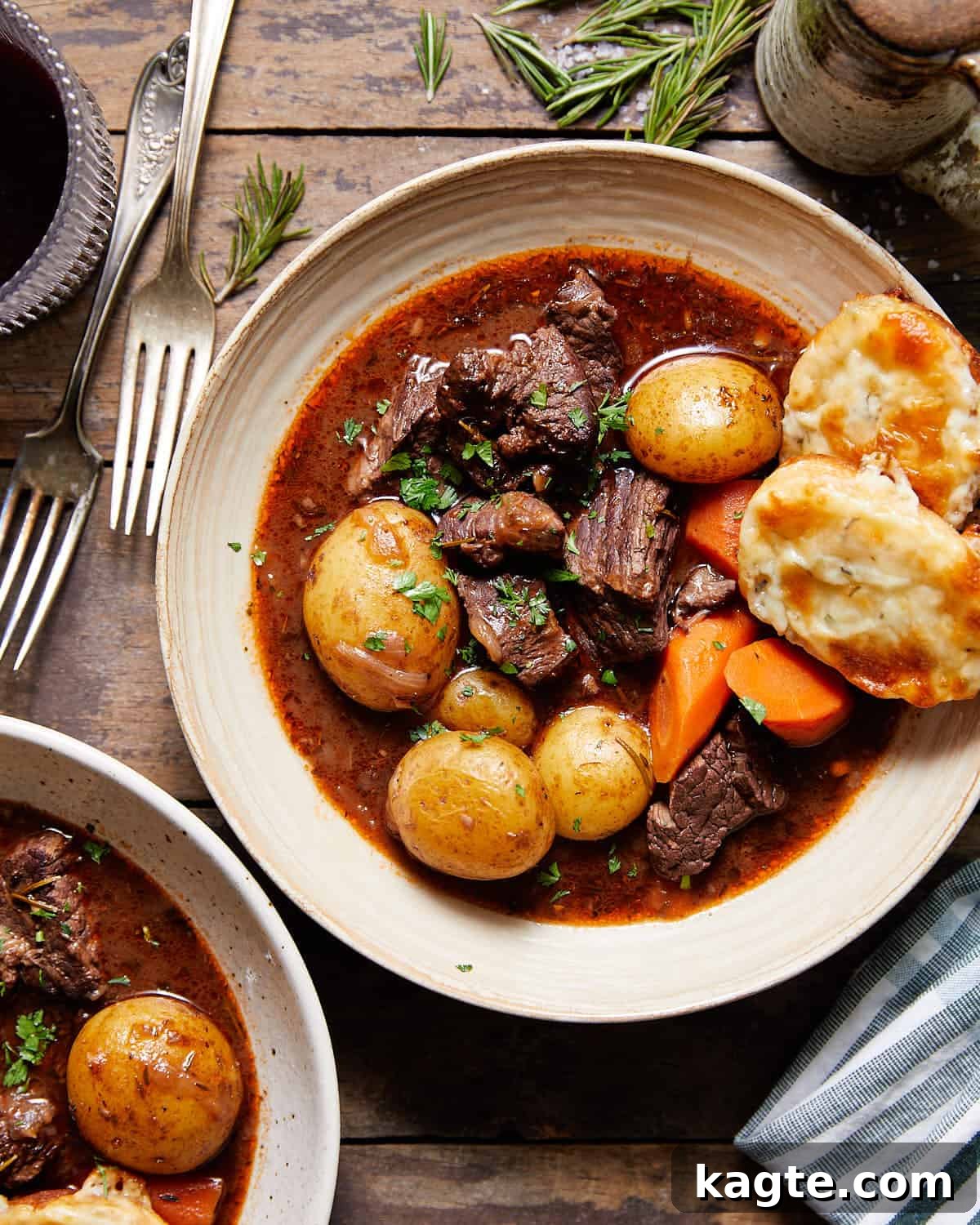 Dutch Oven Red Wine Beef Stew 2 Overhead image of a steaming Dutch oven beef stew in a bowl with fresh herbs and crusty bread.