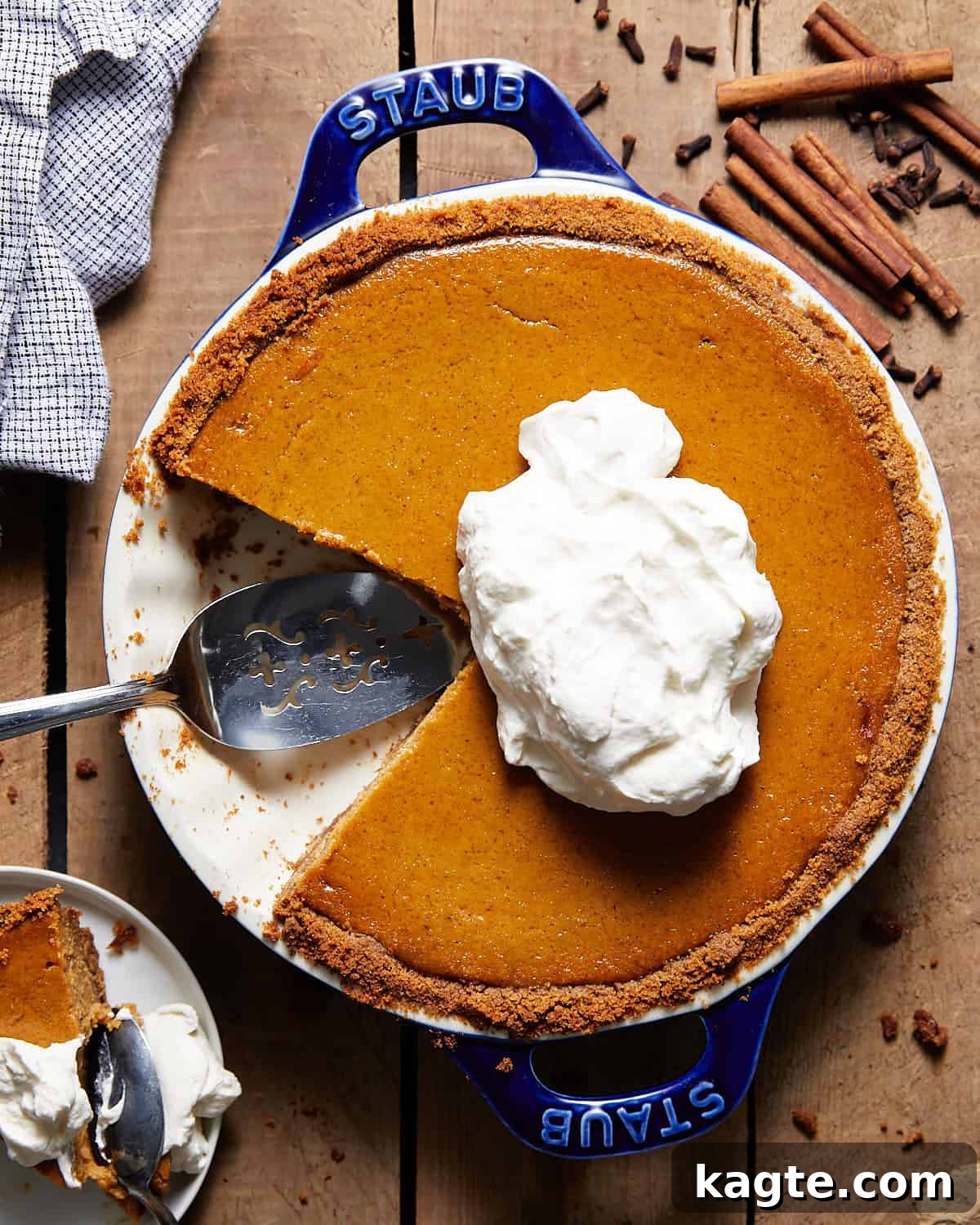 A beautifully baked pumpkin pie with a golden graham cracker crust, presented in an elegant blue pie dish, ready to be served. The texture of the filling is smooth and the crust is perfectly golden.