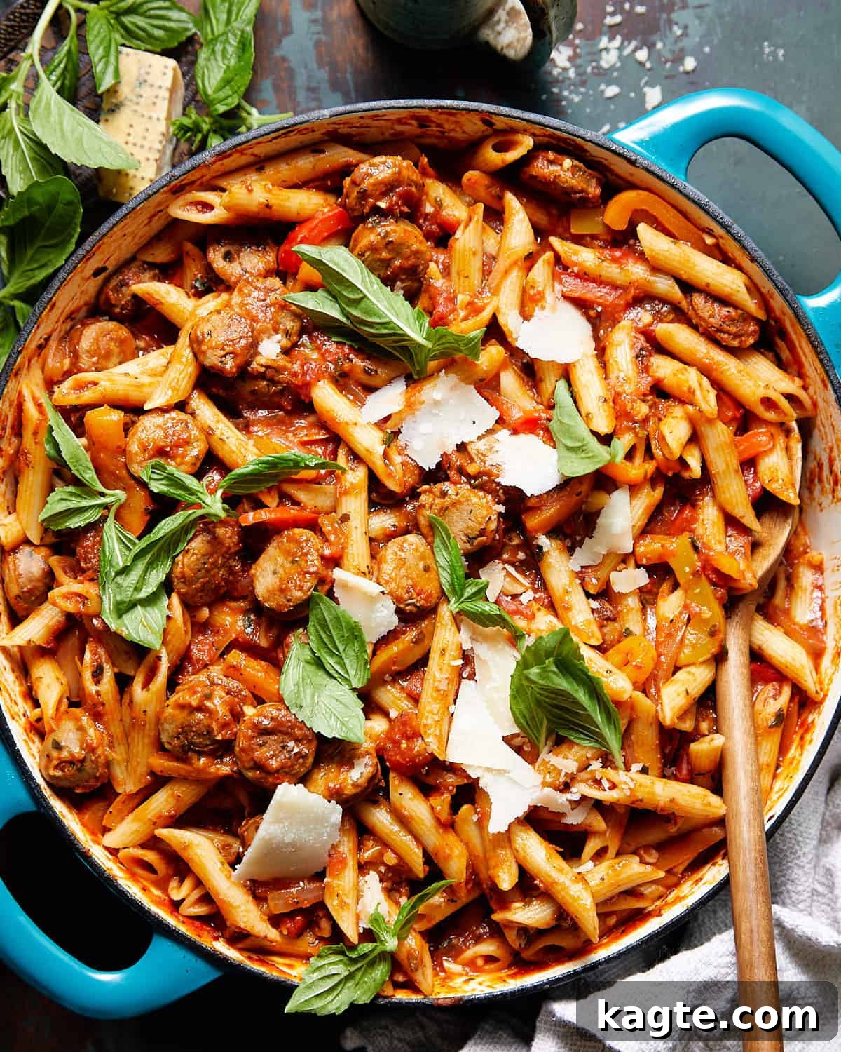 Quick Weeknight Sausage and Pepper Pasta 2 Sausage and peppers pasta with fresh basil and grated parmesan in a blue pot, ready to serve.