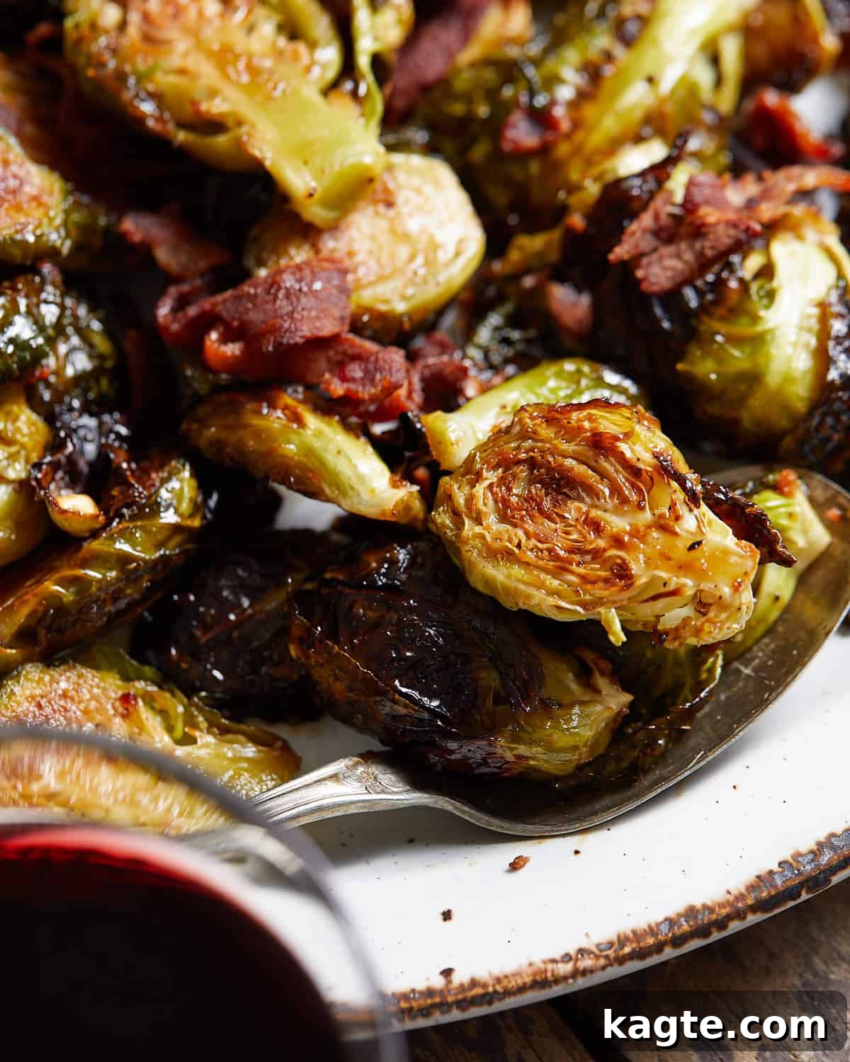 Up close image of crispy glazed brussels sprouts, showing the glistening glaze and bacon bits.