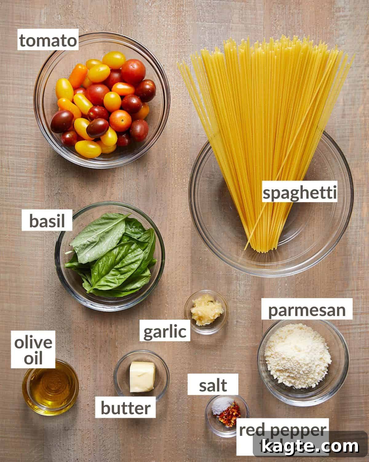 Vibrant Basil and Sweet Cherry Tomato Pasta 3 Glass bowls neatly arranged with the fresh ingredients required for tomato basil pasta: spaghetti, cherry tomatoes, minced garlic, fresh basil, grated Parmesan cheese, butter, and olive oil.