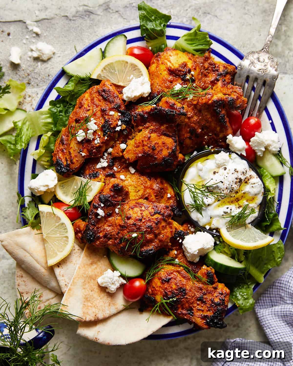 A vibrant platter of Greek yogurt marinated chicken, garnished with fresh herbs and lemon slices, ready to be served.