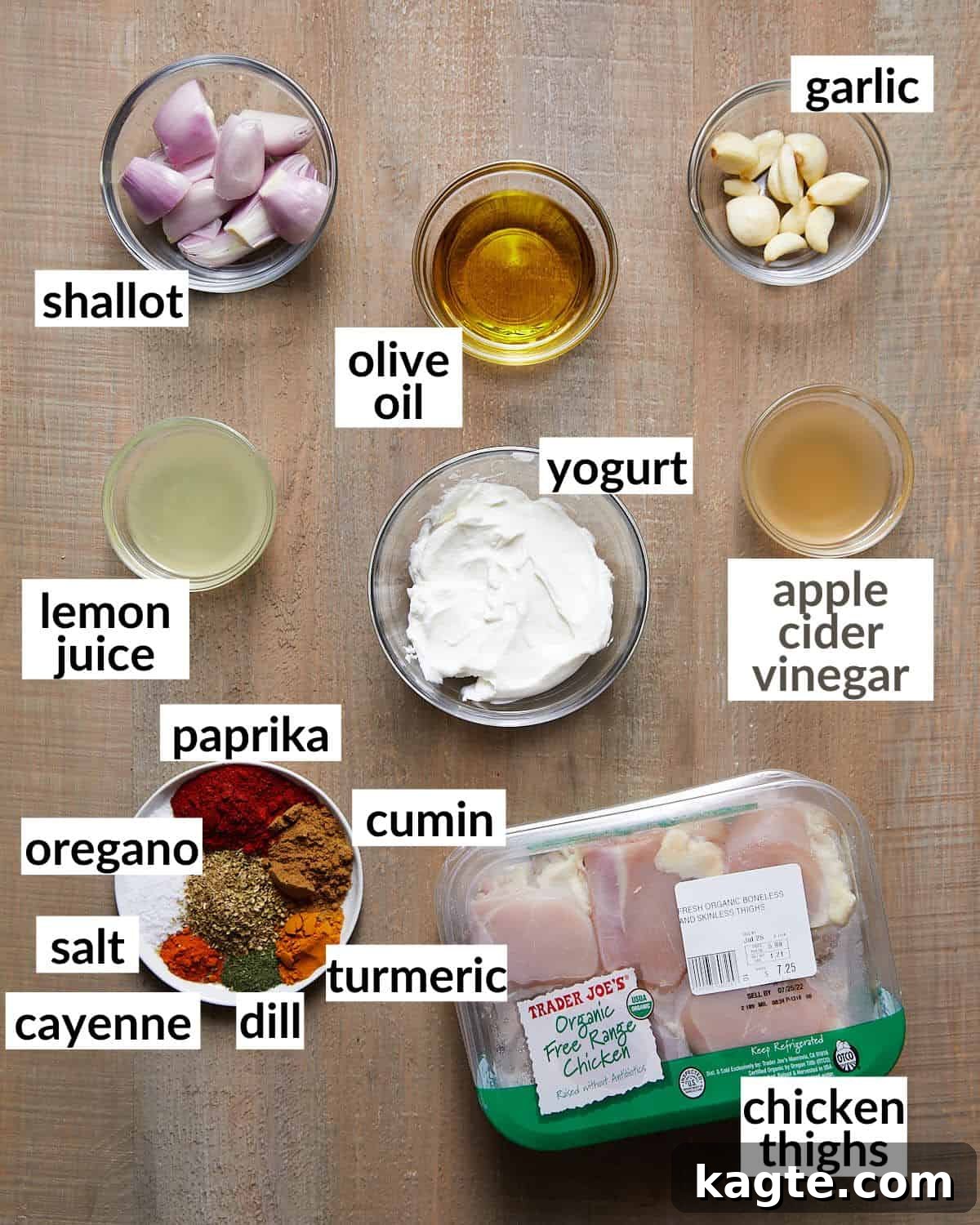 A collection of fresh ingredients for Greek yogurt chicken, including Greek yogurt, olive oil, lemon, shallots, garlic, and an assortment of colorful spices, neatly arranged in glass bowls.