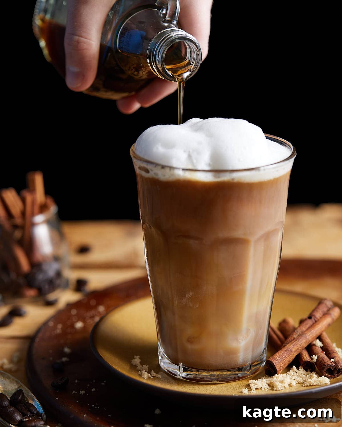 Brown sugar syrup being poured into coffee.