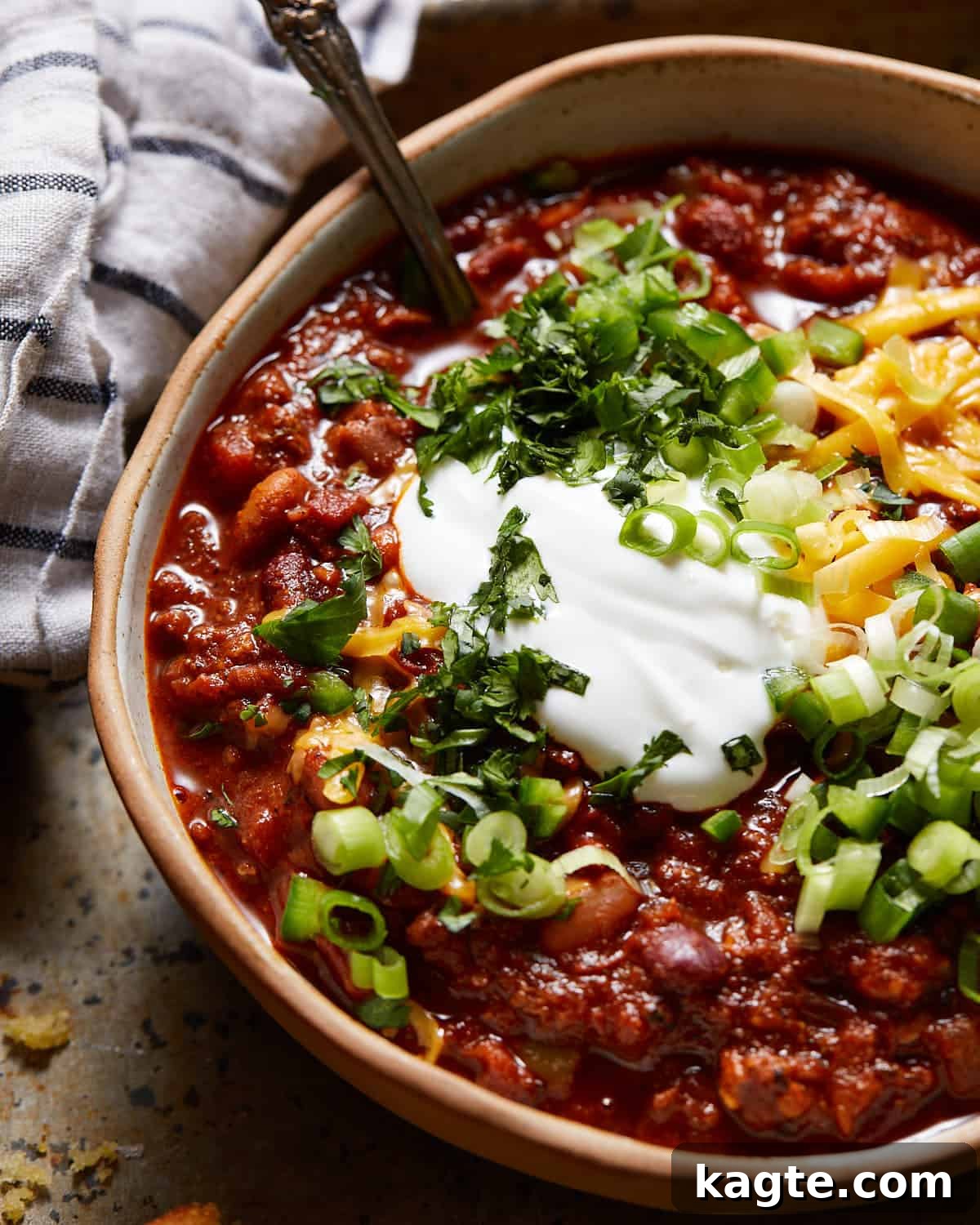 Cast-Iron Comfort Chili 6 A beautifully presented bowl of Dutch oven chili, lavishly topped with shredded cheese, sour cream, and fresh cilantro, ready to be enjoyed.