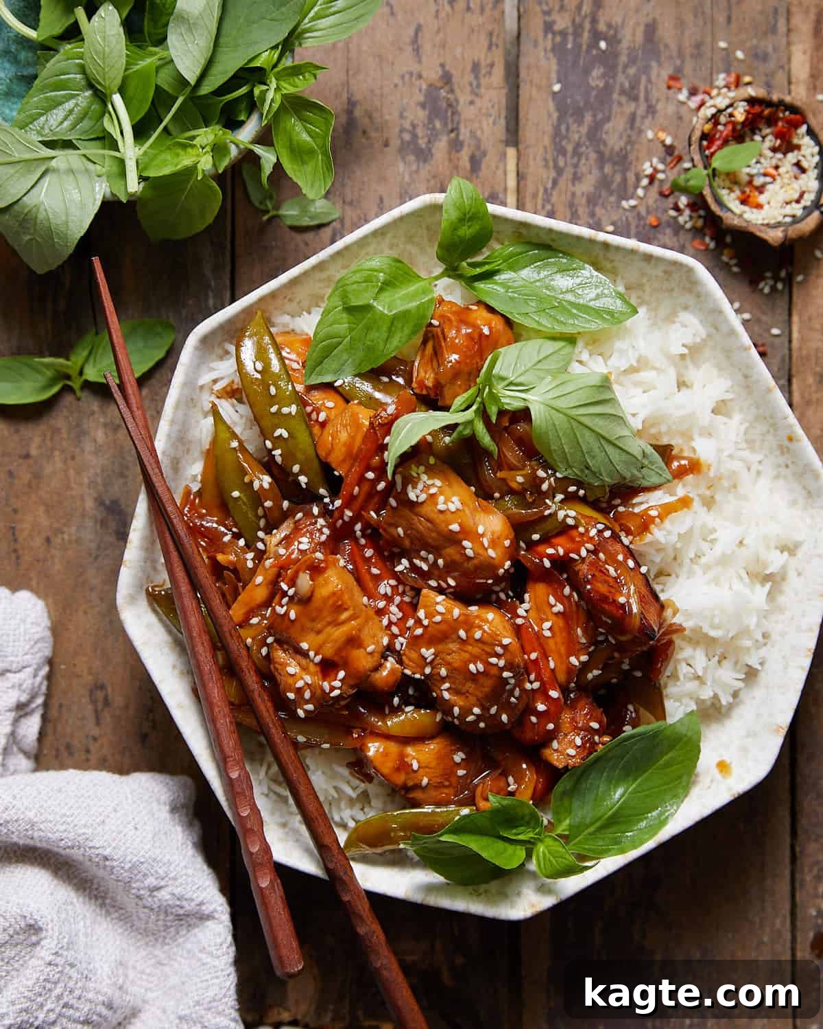 Stir fry marinated chicken and veggis over rice in a bowl.