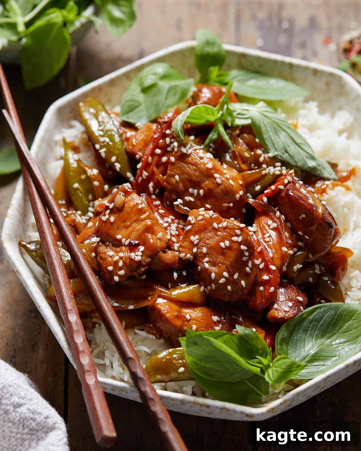 Chicken stir fry over rice in a bowl with chopsticks.