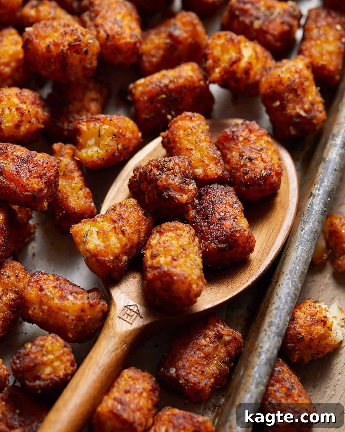 Close-up of crispy seasoned tater tots on a wooden spoon, ready to be served.