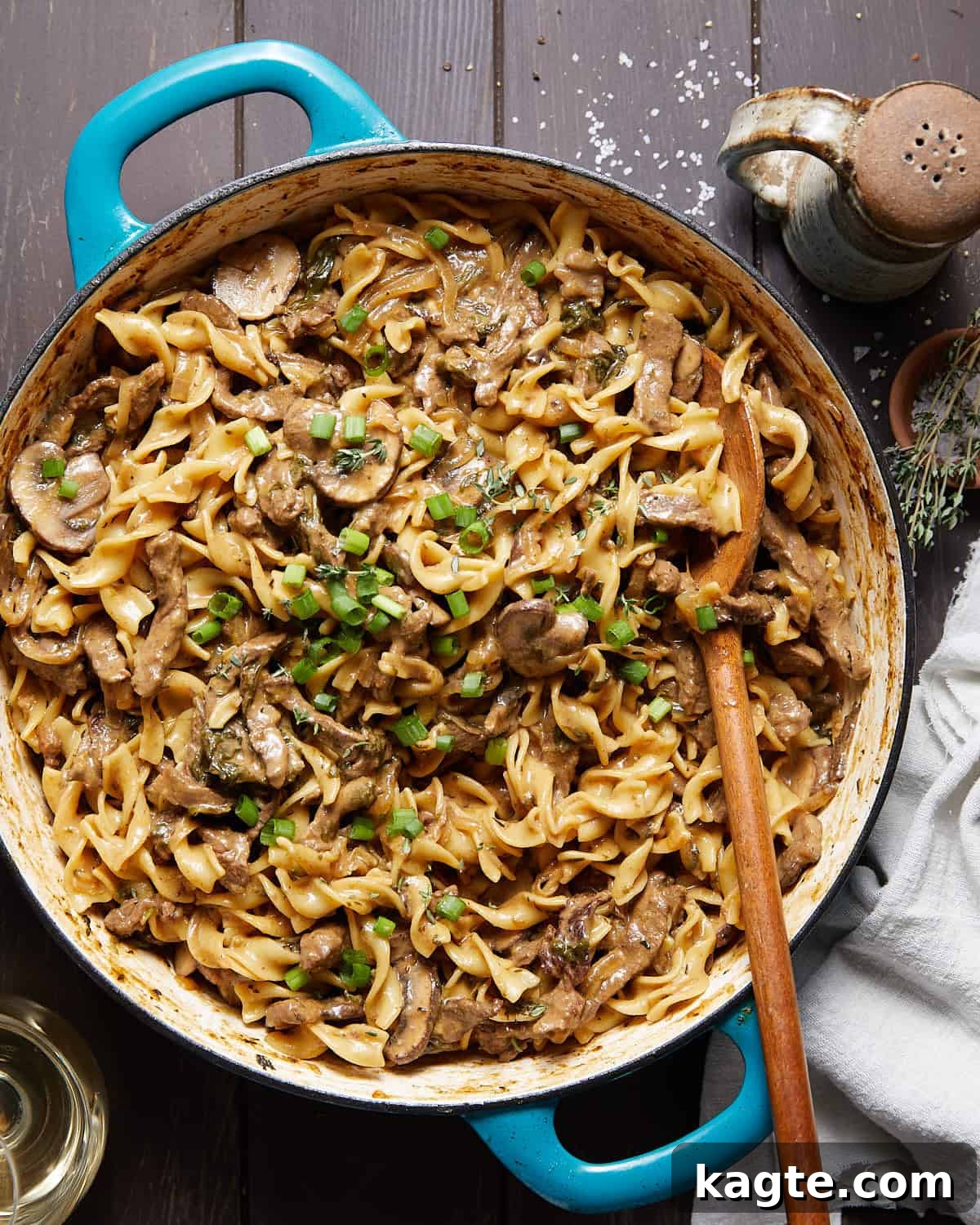 Photo of healthy beef stroganoff in large blue pan, garnished with fresh herbs.