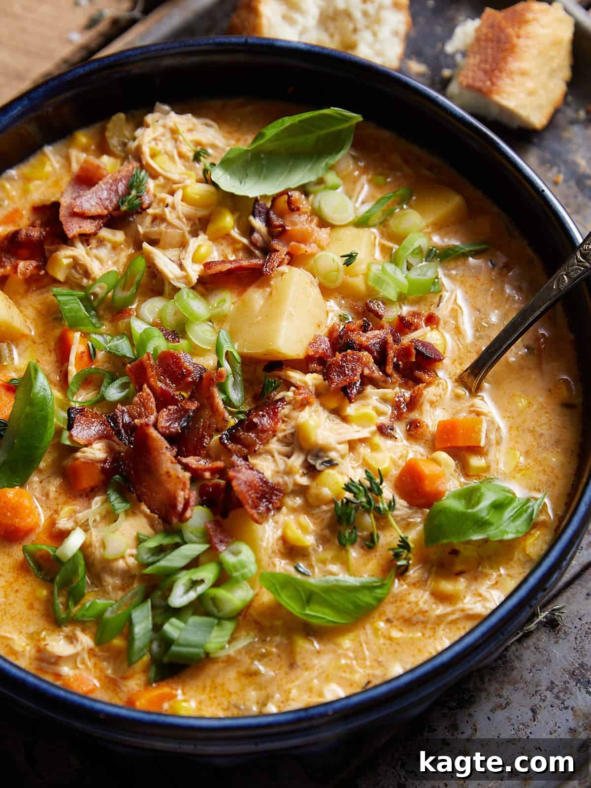 Hearty Slow Cooker Creamy Chicken Corn Chowder 6 An appetizing close-up of creamy chicken and corn soup, garnished with vibrant fresh herbs and crispy bacon, served in a rustic blue bowl, emphasizing the rich texture and appealing presentation.
