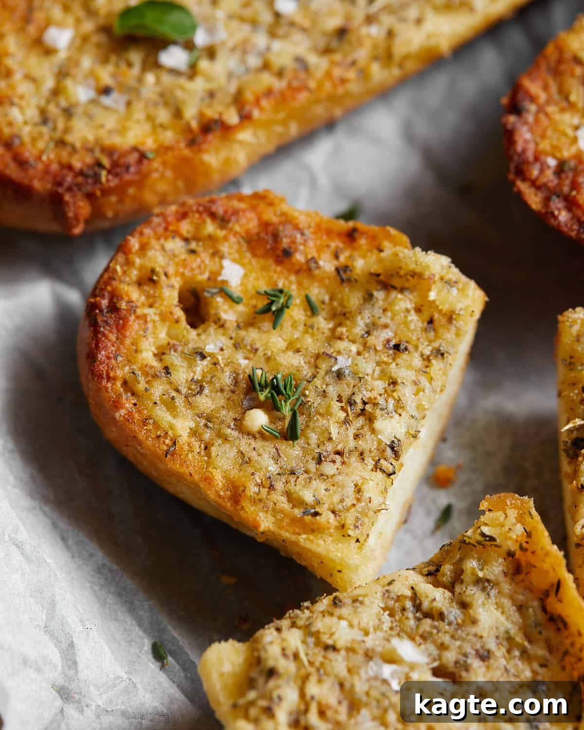 Detailed close-up image of a perfectly baked slice of cheesy garlic bread, showing the golden crust and melted spread.