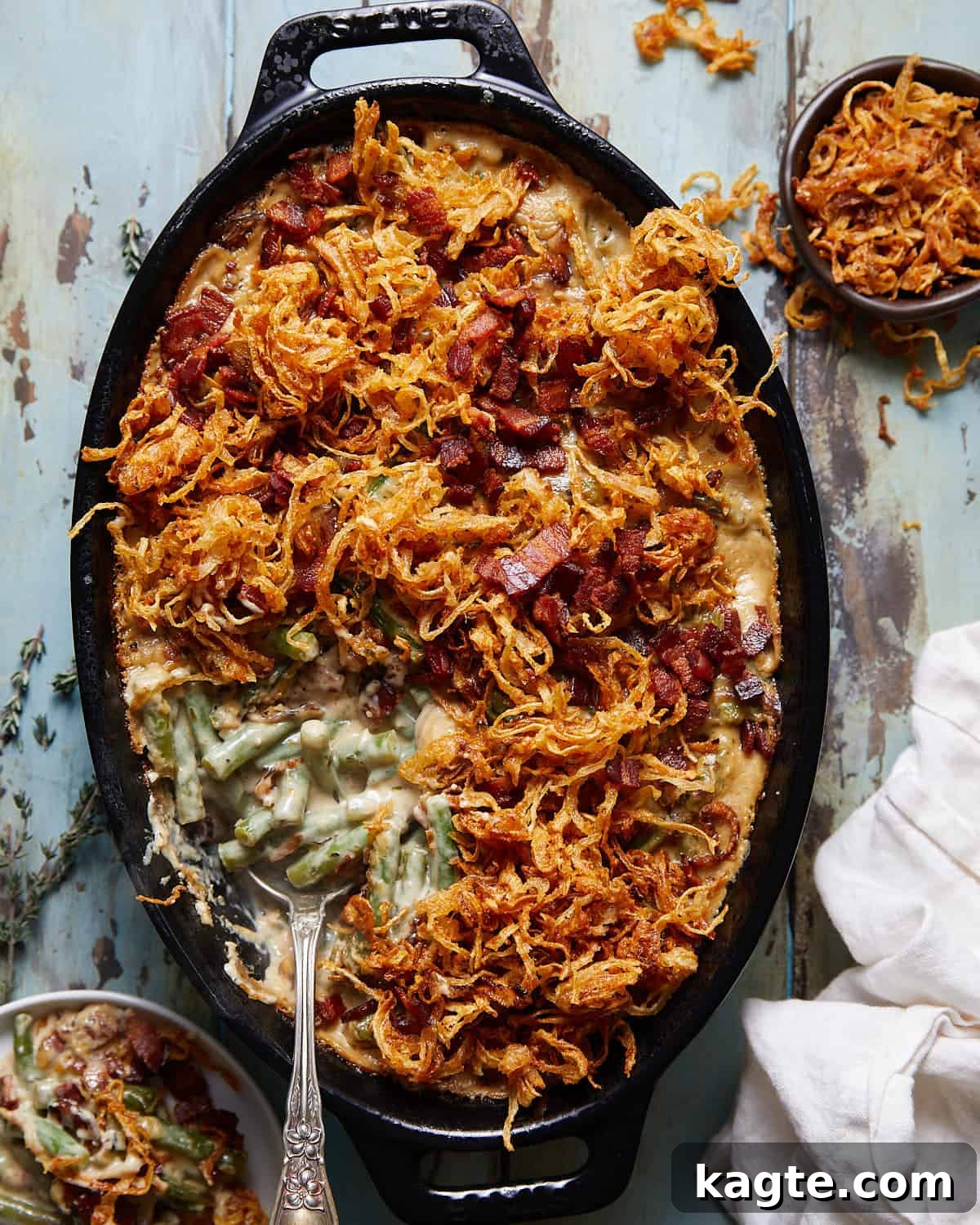 Savory Green Bean Casserole with Bacon and Earthy Mushrooms 2 Overhead image of green bean casserole with bacon and mushrooms, garnished with crispy onions and fresh herbs.