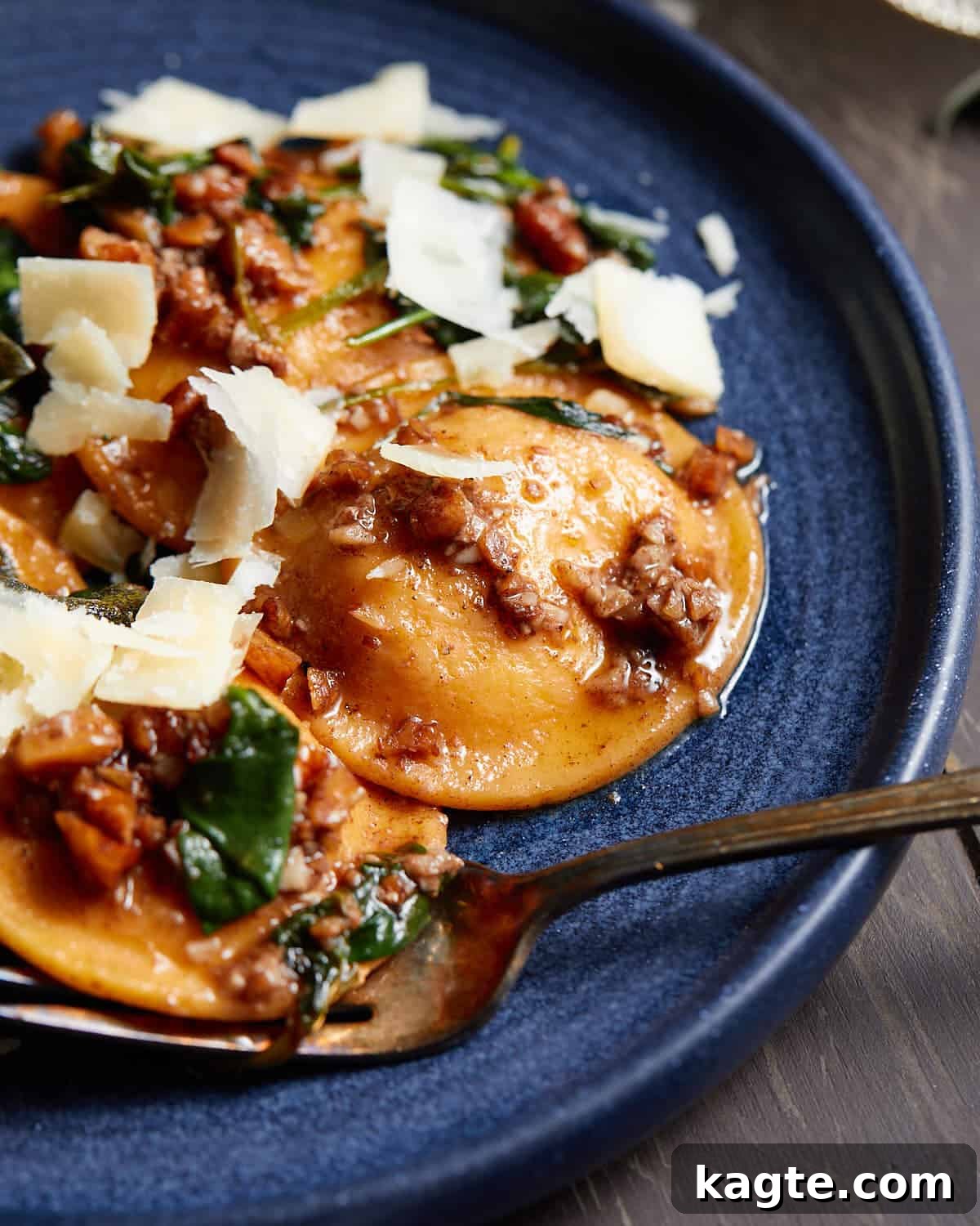 Velvety Butternut Squash Ravioli Sauce 6 Up close image of butternut squash ravioli sauce on blue dish with garnish.
