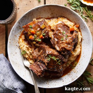 A beautifully plated dish of red wine short ribs, mashed potatoes, and greens.