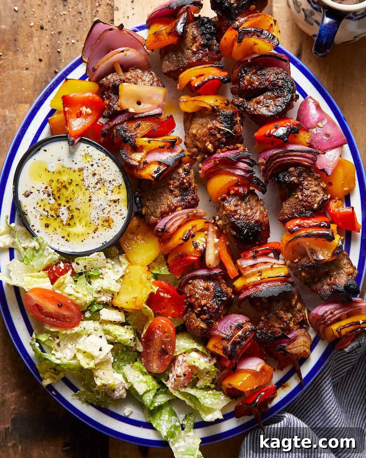 Tender Oven-Baked Beef Skewers 2 Overhead image of beef kabobs on white and blue dish.