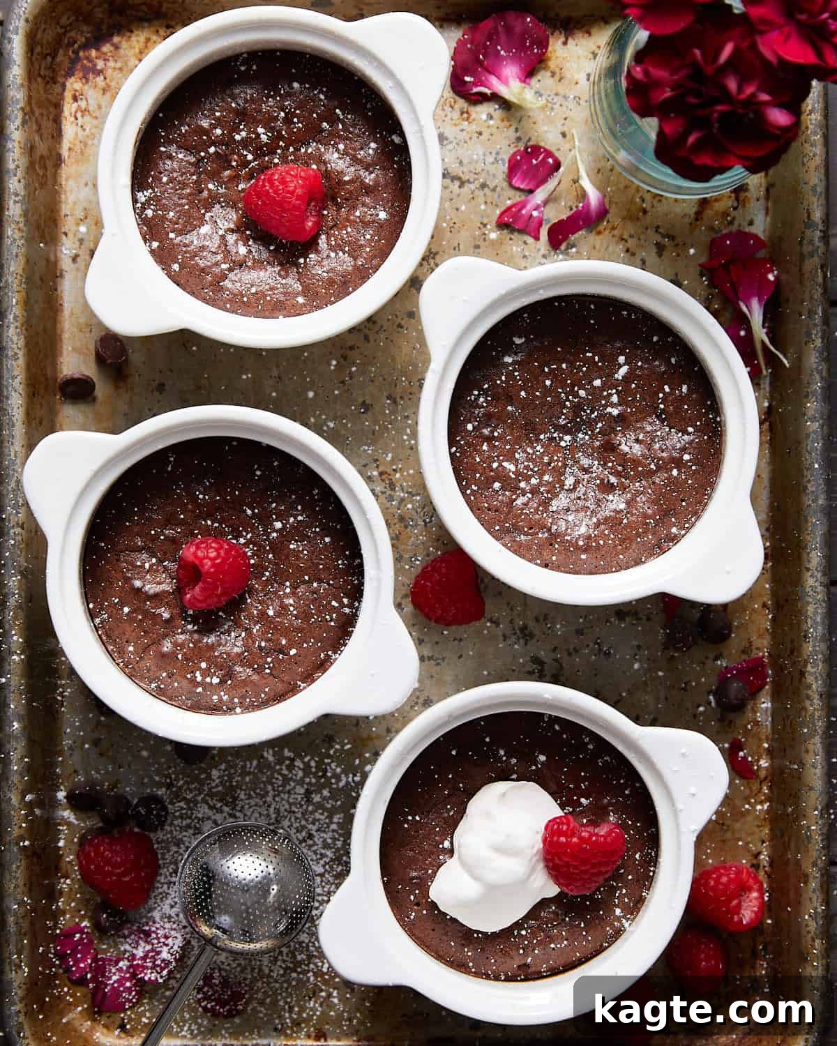 Overhead image of four individual mini flourless chocolate cakes in elegant white dishes, garnished with fresh berries.