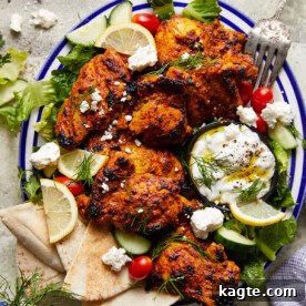 Tender Greek yogurt chicken served elegantly on a white and blue dish with fresh garnish.