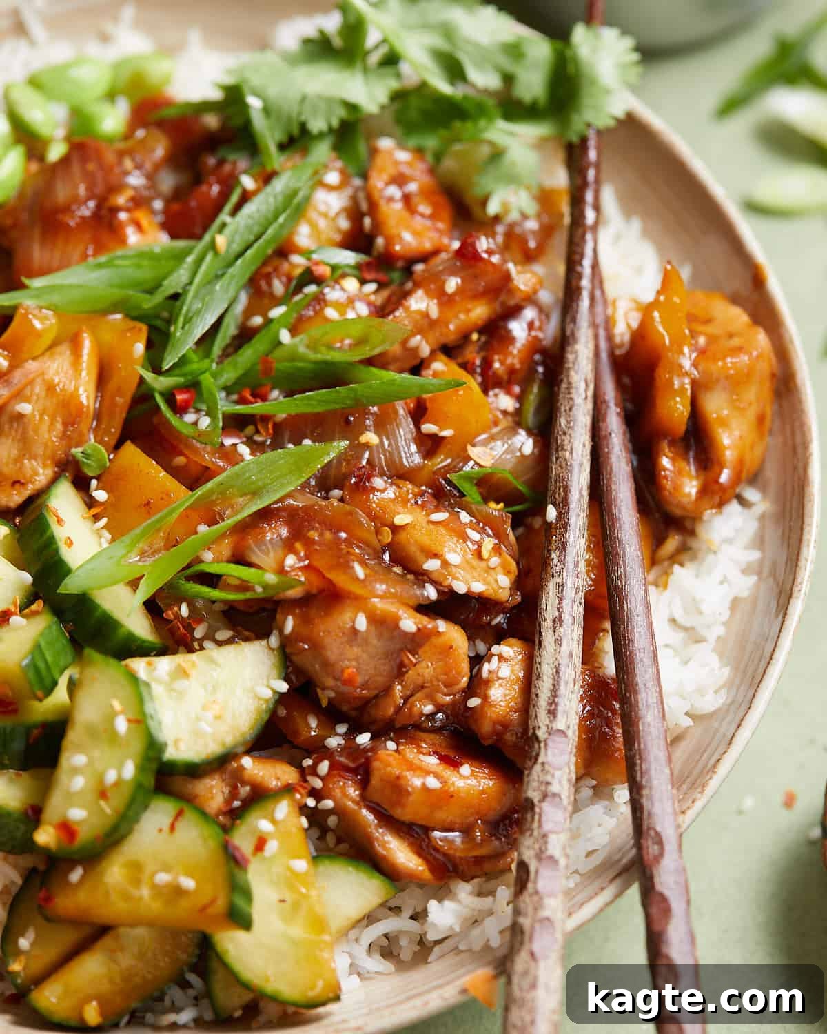 Up close image of a vibrant teriyaki chicken bowl with chopsticks, ready to be enjoyed.