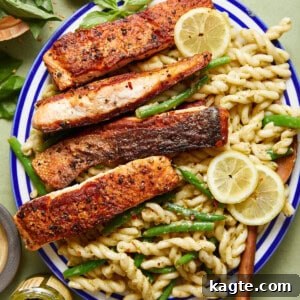 A plate of easy salmon pasta without cream, garnished with fresh basil and a lemon wedge.