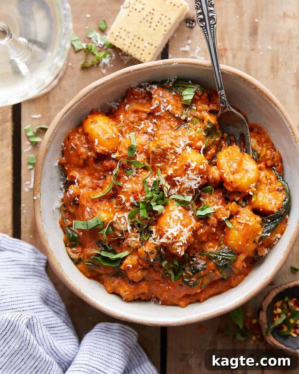 Creamy Sausage Gnocchi with Tomato and Spinach 2 Overhead view of a rustic skillet filled with rich, creamy sausage gnocchi, vibrant spinach, and fresh basil garnish, ready to be served.