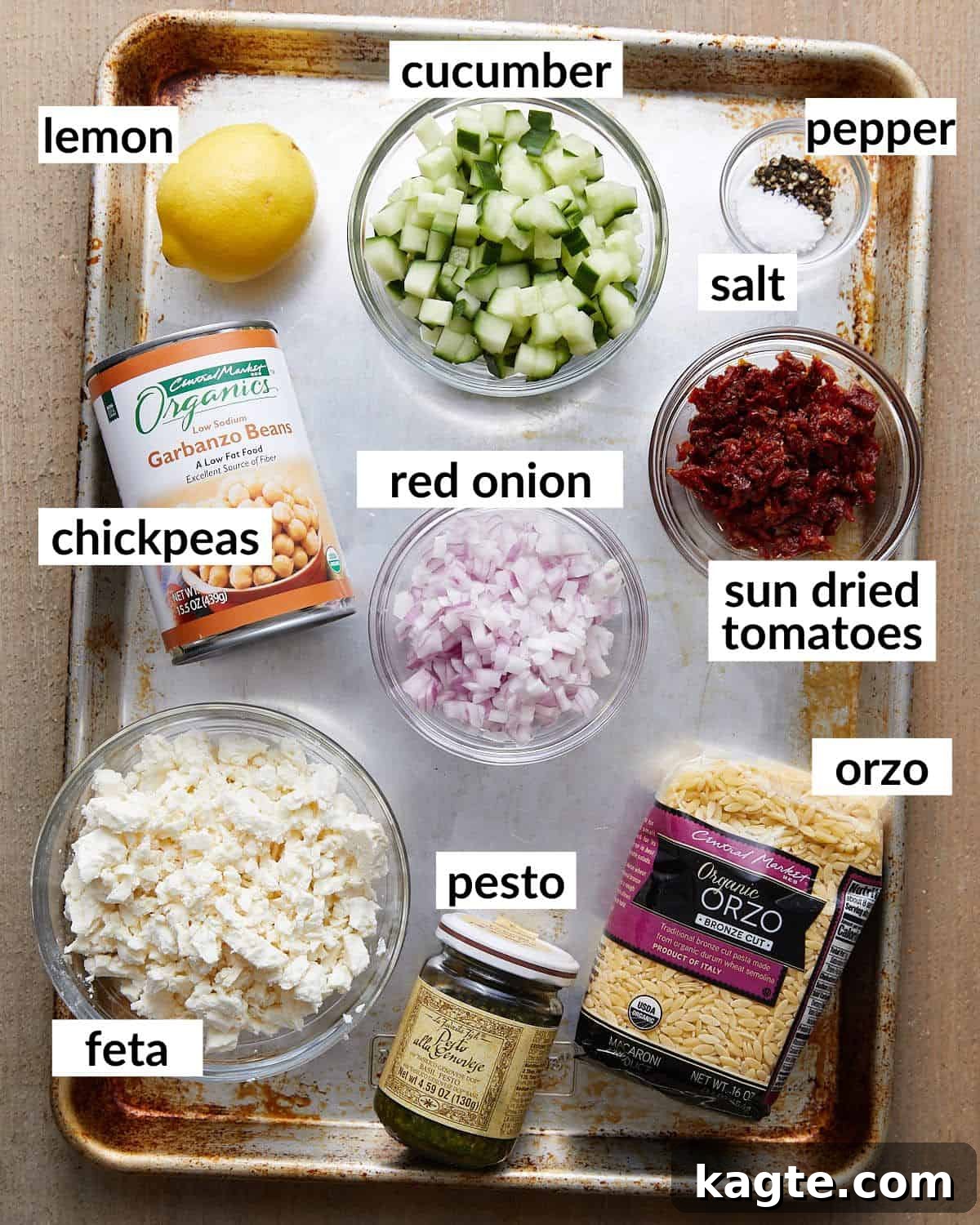 Effortless Pesto Orzo Salad 3 Overhead image of fresh ingredients laid out for making pesto orzo salad, including orzo, chickpeas, vegetables, and feta.