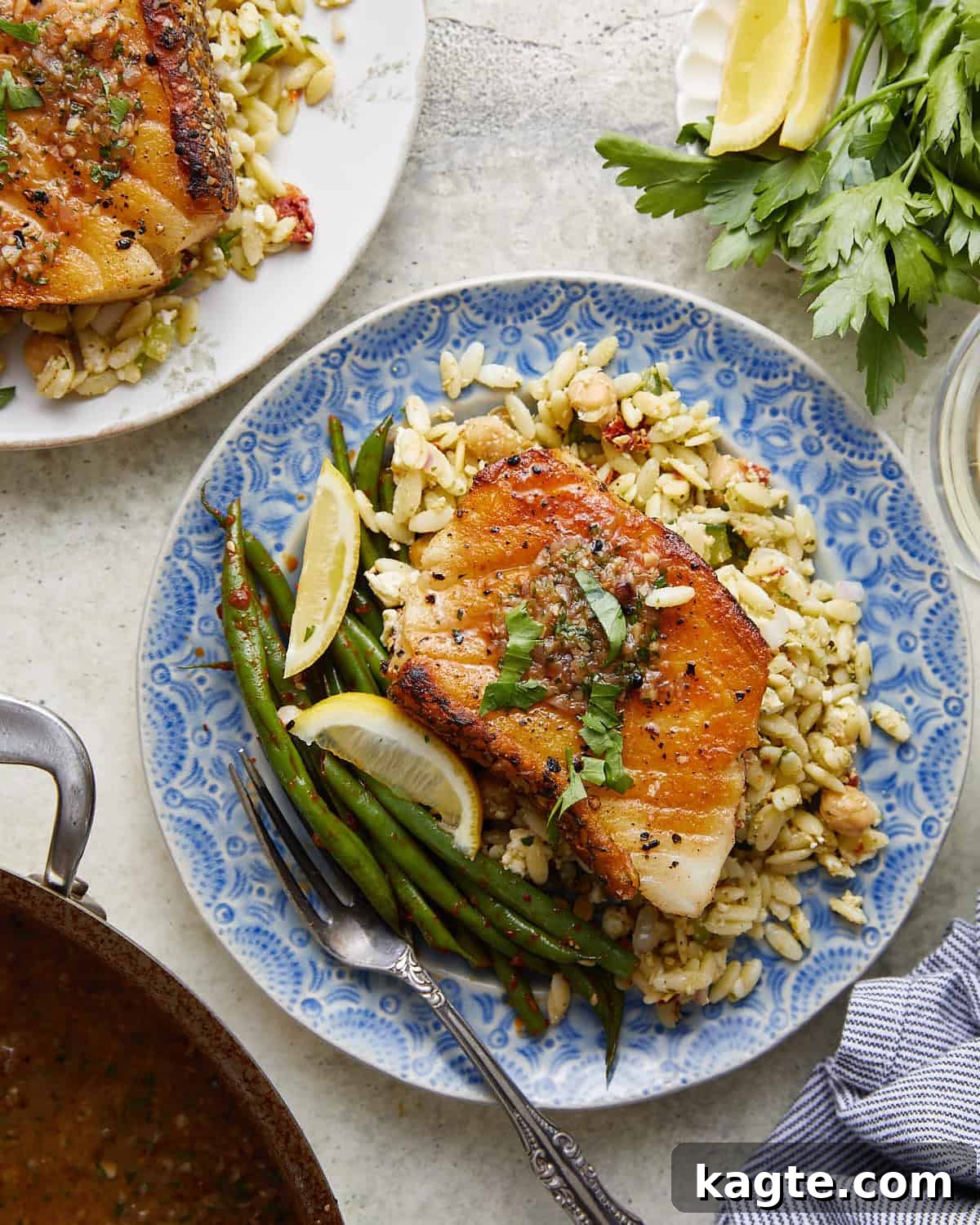 Overhead image of perfectly pan seared Chilean sea bass fillets, garnished with fresh herbs and a luscious white wine lemon butter sauce, ready to be served.