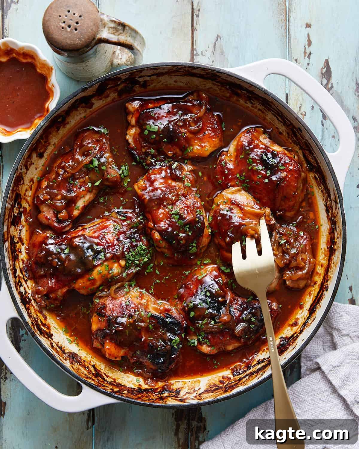 An overhead image of Dutch oven BBQ chicken, garnished with fresh herbs, ready to be served from the pan.