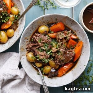Close-up image of a perfectly cooked old fashioned pot roast, shredded and garnished, ready to be served.