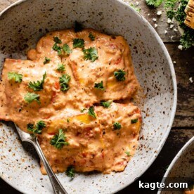 A plate of pink sauce for lobster ravioli, garnished with fresh herbs and a hint of cheese.