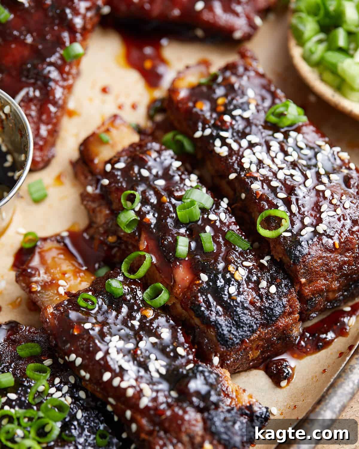 Finger-Licking Asian Oven Ribs 2 Up close image of sticky asian ribs with garnish.