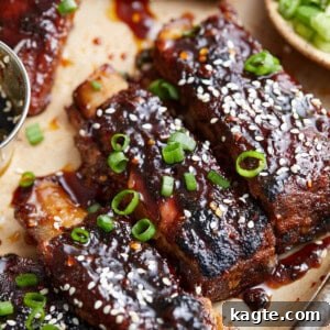 A plate of sticky Asian pork ribs, garnished with sesame seeds and green onions.