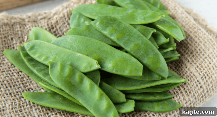 Close-up view of fresh, flat snow peas, highlighting their smooth, edible pods.