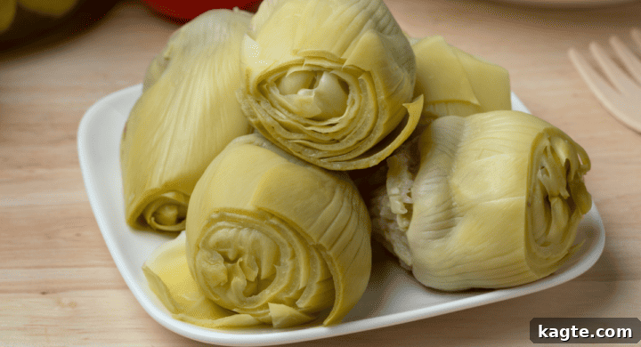 Canned or jarred artichoke hearts, preserved in liquid, some whole and some halved.