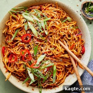 A bowl of delicious Chili Garlic Noodles garnished with green onions and sesame seeds.