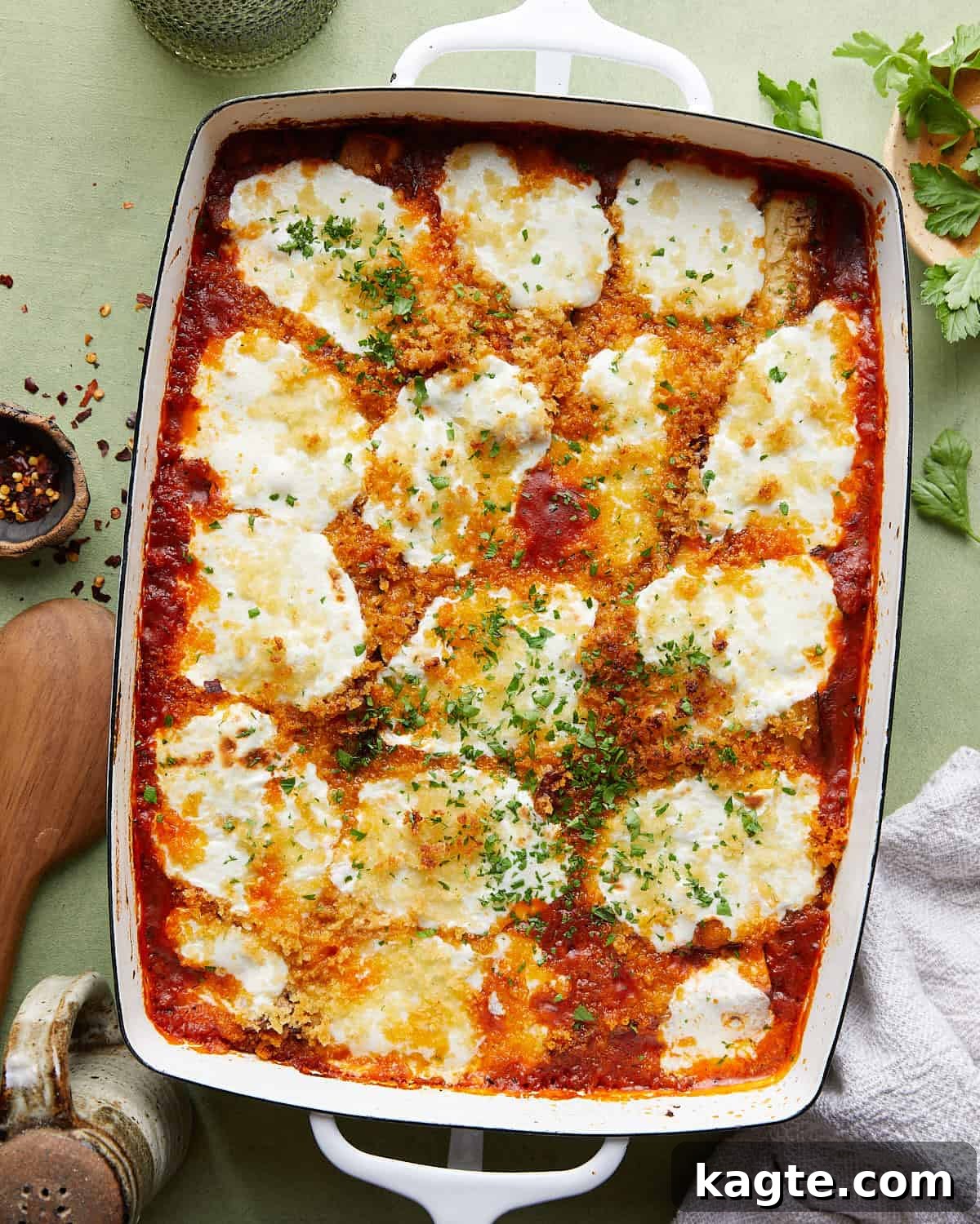 Overhead image of Italian baked zucchini with rich tomato sauce and golden-brown cheese topping, garnished with fresh herbs.