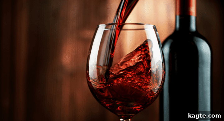 A glass of red wine next to a bottle.