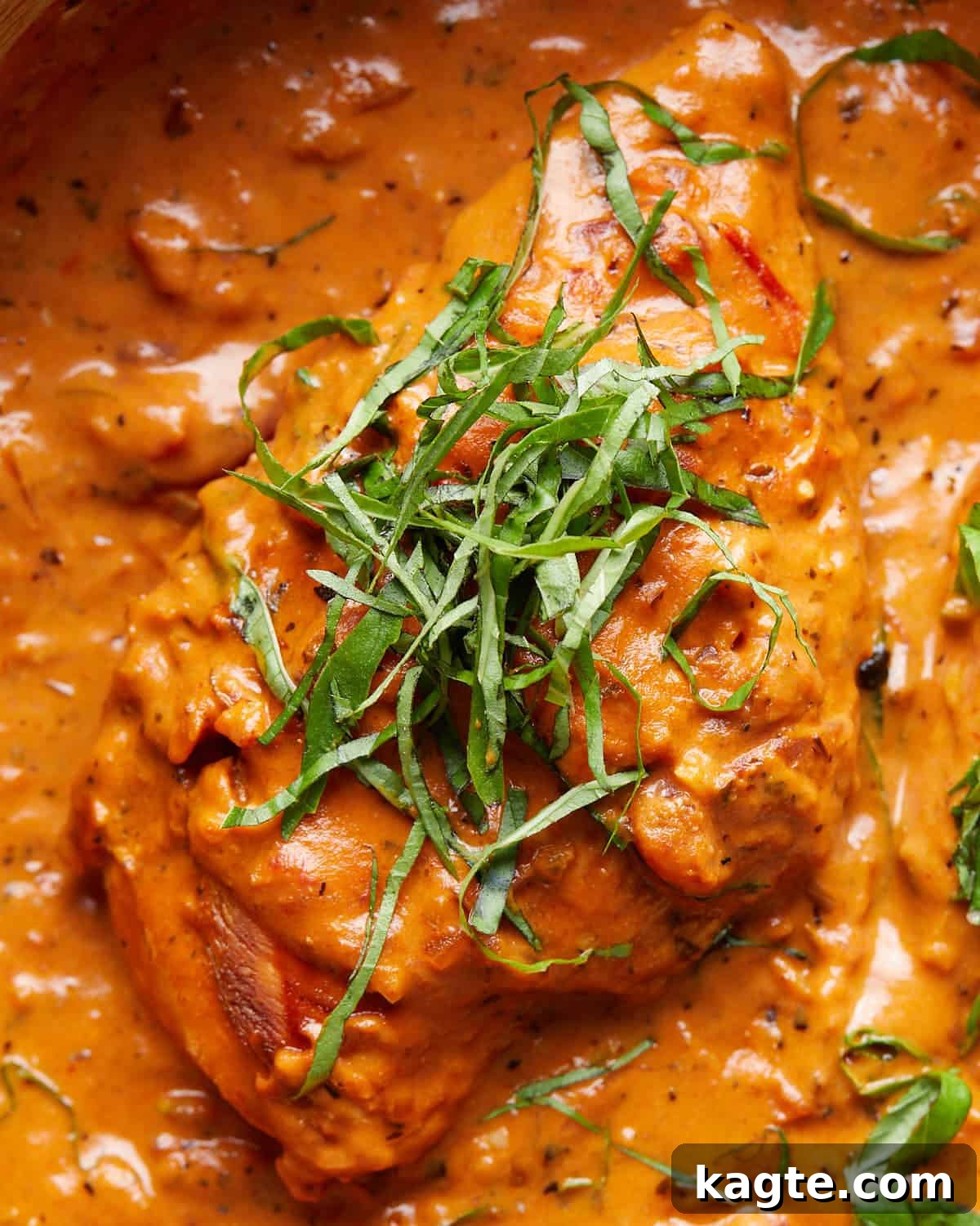 Dreamy Tomato Basil Chicken 6 Close-up image of a succulent piece of creamy tomato basil chicken, generously garnished with fresh basil leaves, ready to be enjoyed.