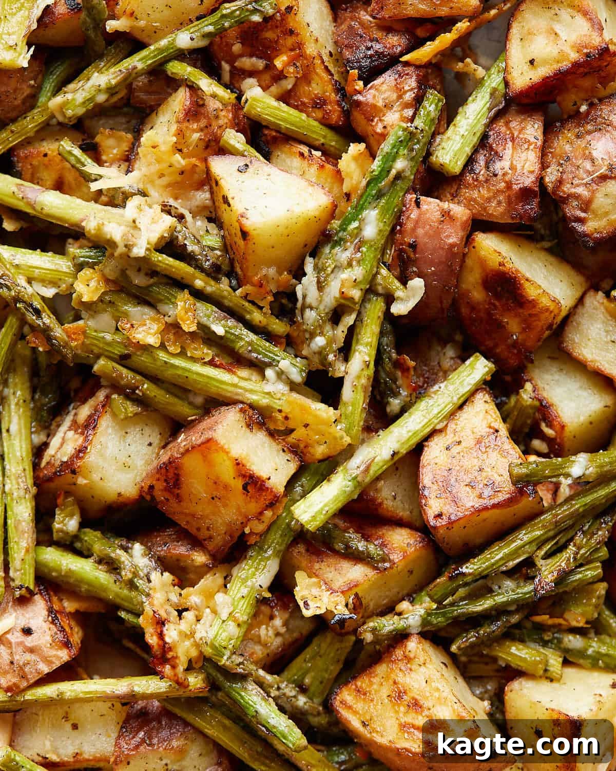 Up close image of perfectly roasted potatoes and asparagus with parmesan cheese and fresh herbs.