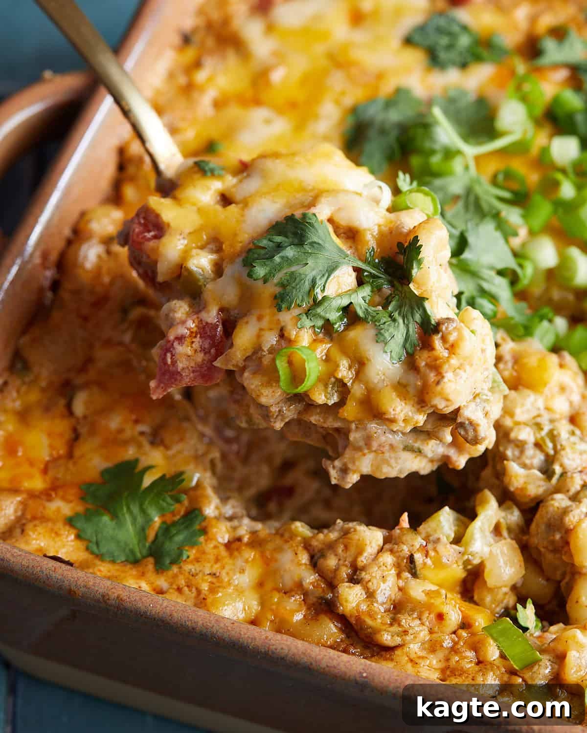 Fiesta Cheesy Taco Pasta Bake 6 Up close image of taco pasta bake with melted cheese and a spoonful taken out, showing the creamy interior.