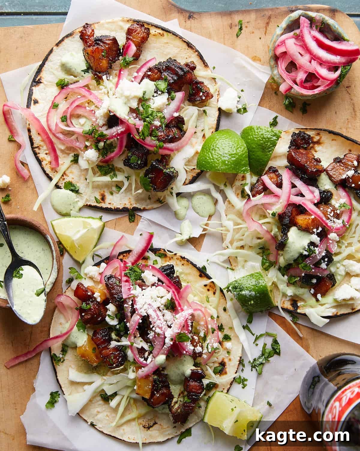 Ultimate Crispy Pork Belly Tacos 2 Overhead image of crispy pork belly tacos with fresh cilantro and lime wedges as garnish.