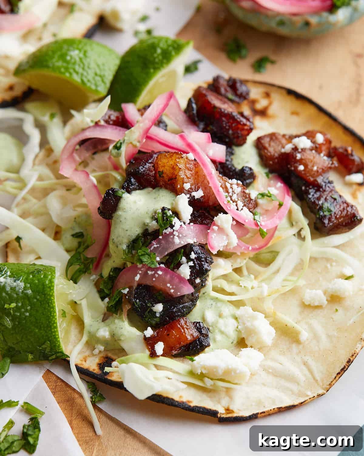 Ultimate Crispy Pork Belly Tacos 5 Up close image of a hand holding a pork belly taco with visible crispy pork, pickled red onions, and cilantro.