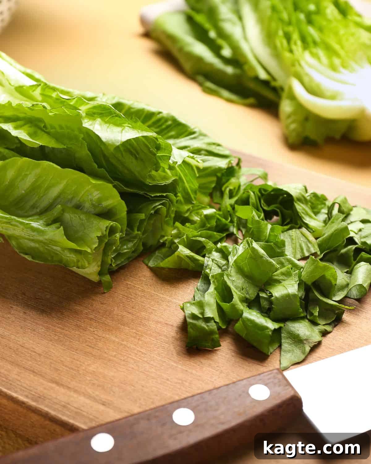 Close-up photo of freshly cut romaine lettuce on a wooden cutting board, ready for a salad.