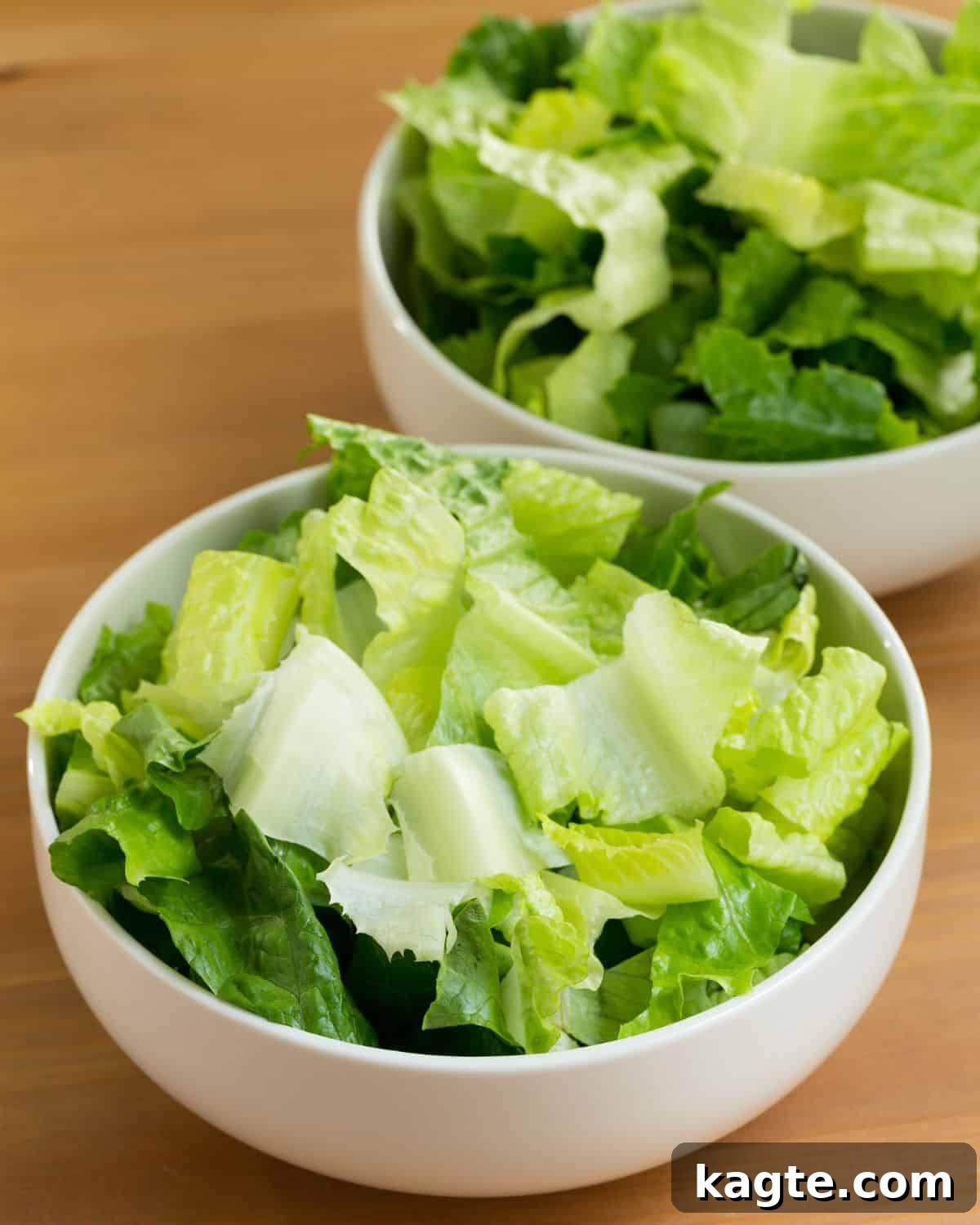 Overhead shot of perfectly chopped romaine lettuce in a white bowl, ready for storage or immediate use.