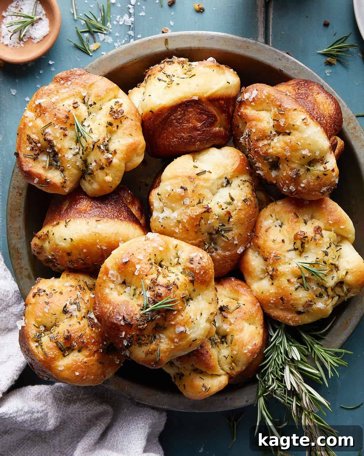 Aromatic Garlic Rosemary Focaccia Bites 2 Overhead image of focaccia muffins garnished with fresh rosemary and flaky salt, arranged appealingly on a serving dish.