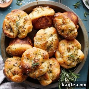 Close-up image of a freshly baked focaccia muffin, garnished with rosemary and flaky salt.